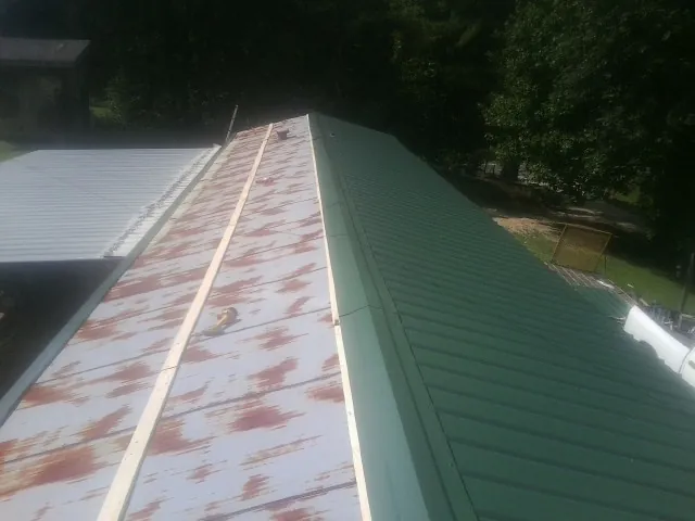 Old rusted panels beside newly installed green metal roofing — Wind Damage Roof Repair by Roofing Brothers in Ivoryton
