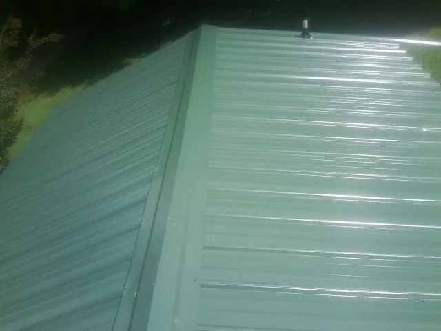 New green metal panels meeting at the ridge of a roof — Flat Roof Repair work by our crew in Ivoryton