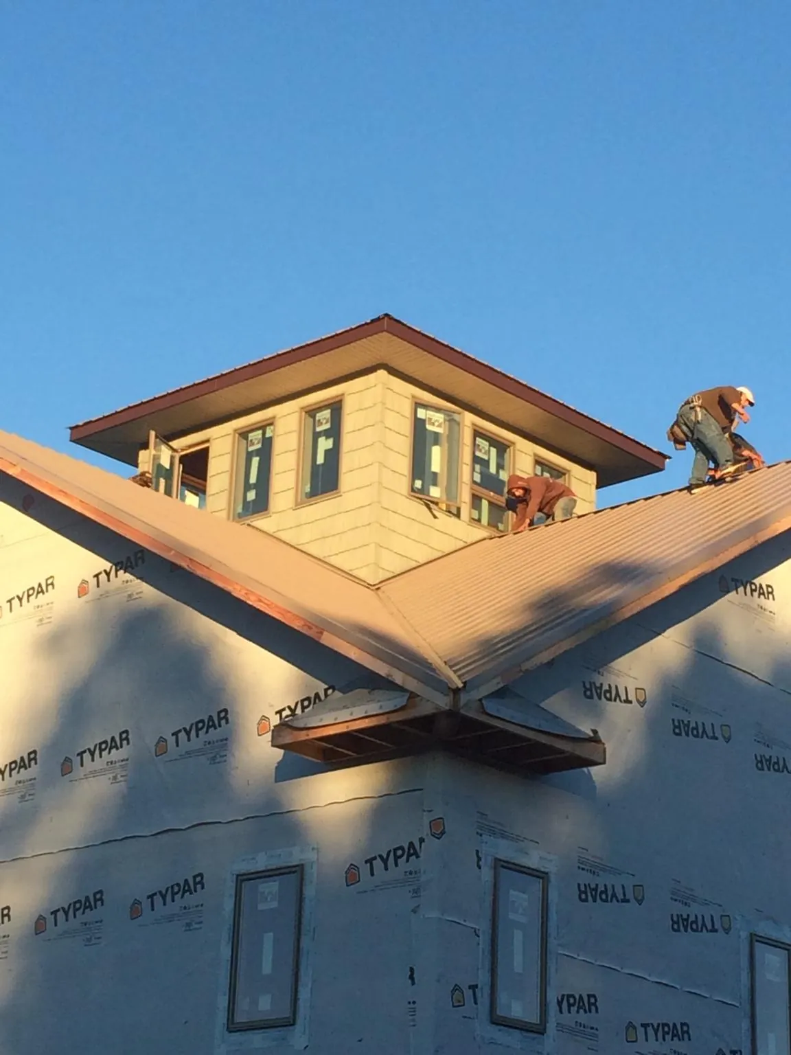 Roofers working around a rooftop cupola on a new metal roof at sunset — Roof Waterproofing in Ivoryton by Roofing Brothers